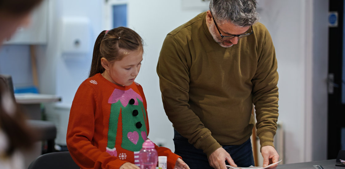 Adult teaching child festive crafts